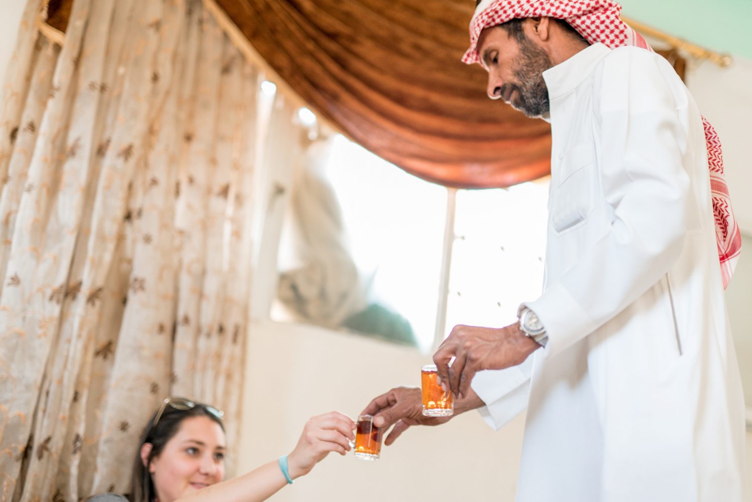 Bedouin man serving tea to a woman on a Jordan tour in Wadi Rum