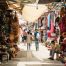 Travelers in the Tunis Medina walk on a narrow street in a colorful bazaar