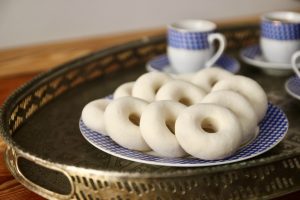 Tunisian kaak warka on a plate with traditional coffee cups in the background